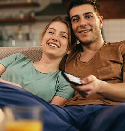 Casal sorrindo no sofá, aproveitando momento de descanso em casa